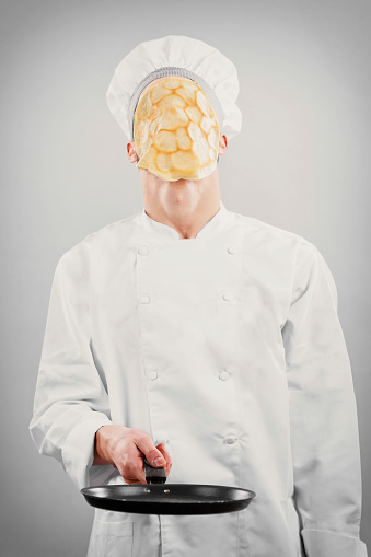 Kitchen chef with pancake on face on gray background