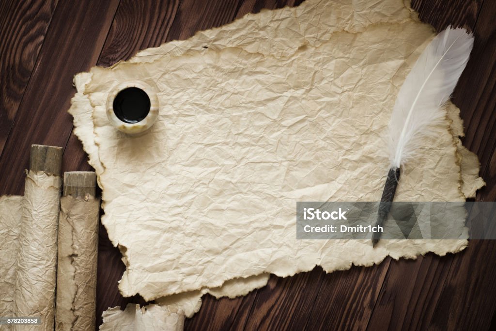 white feather and ancient scroll on brown plank Old paper, scroll and quill pen on wooden paper with copy space Ancient Stock Photo