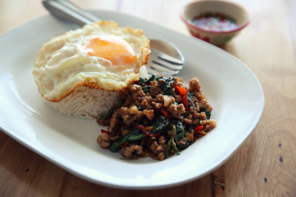 istock stir fried pork and basil with rice and egg on wood background thai food 878210130