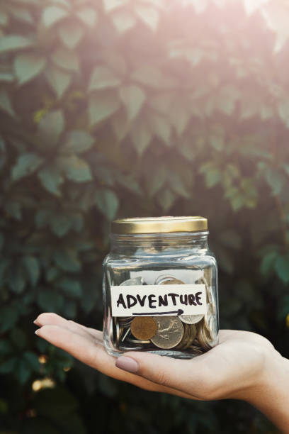 istock Hand holding glass jar with coins for adventure 878211038