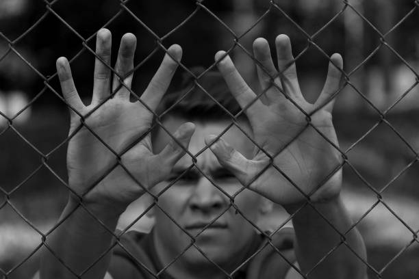 istock A young man behind bars. Imprisonment, famine, war. 878213858