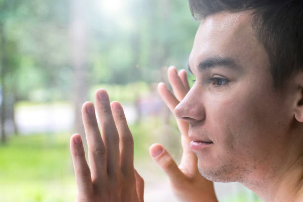 istock The young man sadly looking out the window. Longing, loneliness, boredom 878214536