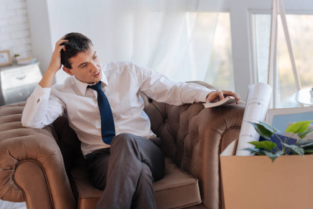 istock Thoughtful young man sitting at home after losing his job 878229794