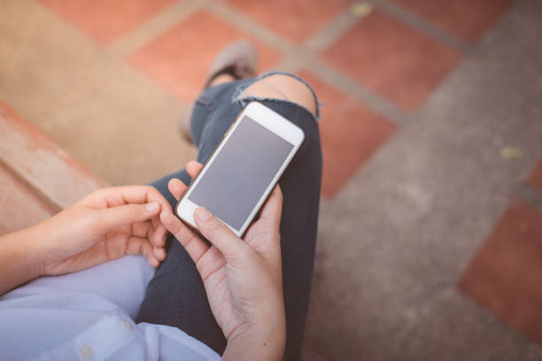 istock Close up female holding smart phone on bench in park 878230350