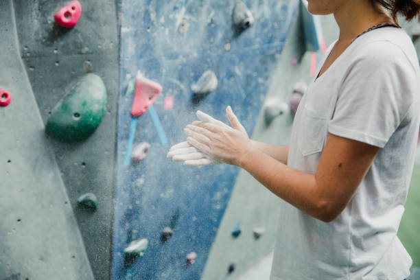 Chalking Hands Ready For Climbing Young woman is dusting her hands with sports chalk in preparation for indoor rock climbing. sports chalk stock pictures, royalty-free photos & images
