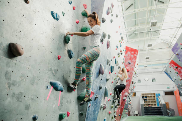 Indoor Rock Climbing Session Women are enjoying a climbing session in an indoor rock climbing centre. clambering photos stock pictures, royalty-free photos & images