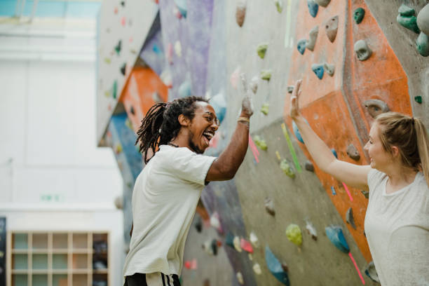 You Did It! Fitness instructor is giving a high-five to a young woman he has been teaching after watching her progress. rock climbing stock pictures, royalty-free photos & images