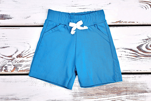 Baby boy light blue shorts. Infant boy textile shorts on white wooden background. Toddler boy boutique outfit.