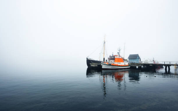 istock A pier with small boats under fog 878257482