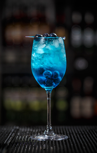 Glass of blue lagoon cocktail decorated with cranberry