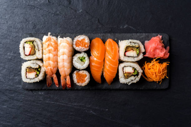 overhead shot of japanese sushi on black concrete background - sushi imagens e fotografias de stock