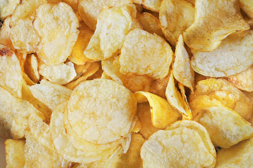 Close-up, overhead image of potato crisps, ideal for use as a background.