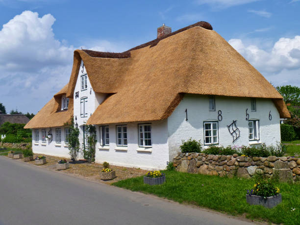 Traditional Frisian thatched cottage on the island of Amrum, Germany Nebel, Amrum, Germany - May 28th, 2016 - Traditional Frisian thatched cottage in the village of Nebel on the island of Amrum. Amrum is famous for its large number of traditional thatched-roof houses which enjoy protected status under monument protection laws. amrum stock pictures, royalty-free photos & images
