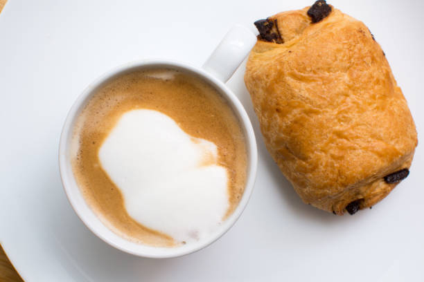 breakfast food on a plate, cappuccino coffee and chocolate croissant