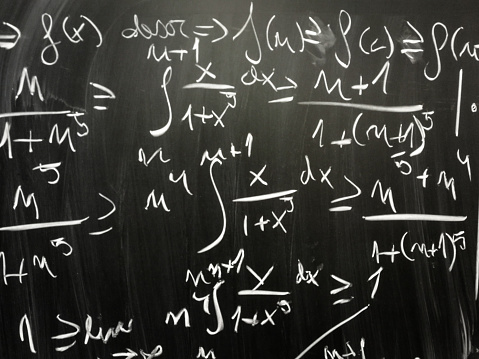 Close up image depicting complex mathematical equations and algebra written in chalk on a blackboard at school. Room for copy space.