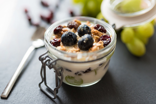 yoghurt with grapes, muesli crumble and cranberries in preserving jar