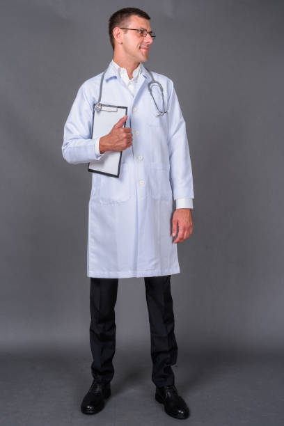 istock Handsome man with doctor wearing eyeglasses against gray background 878336698