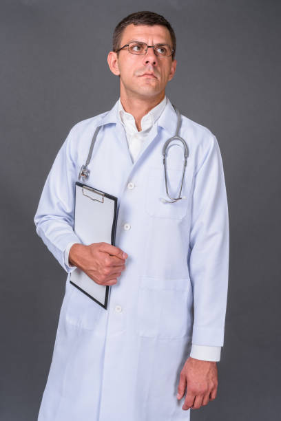 istock Handsome man with doctor wearing eyeglasses against gray background 878336762