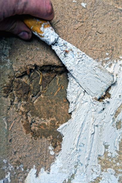 istock hand with a spatula overspreads a hole in the wall 878339112