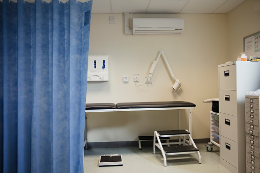Nurse has a conversation with female patient lying in bed during rehabilitation or medical treatment in a ward. View from a surveillance room