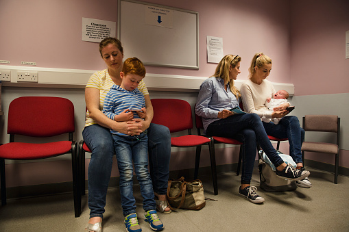Two families sit in the waiting room to see the doctor