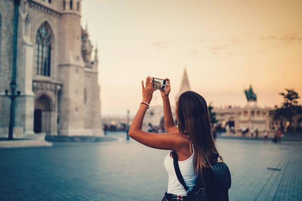 Woman in Budapest photographing the landmarks Tourist in Budapest sightseeing and taking photos with smartphone fishermens bastion photos stock pictures, royalty-free photos & images