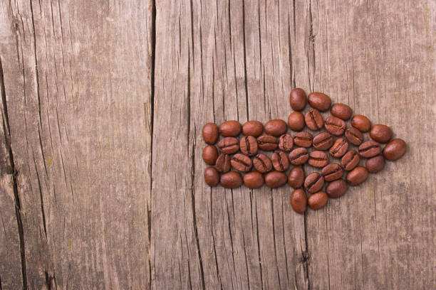 istock Right arrow of coffee beans on an old wooden background. Copy paste text 878361390