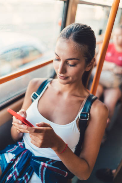 Girl texting in the tram Charming woman traveling and surfing the net on smartphone bus hungary stock pictures, royalty-free photos & images