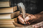 istock Man writing an old letter. Old quill pen, books and papyrus scroll on the table. Historical atmosphere. 878361982