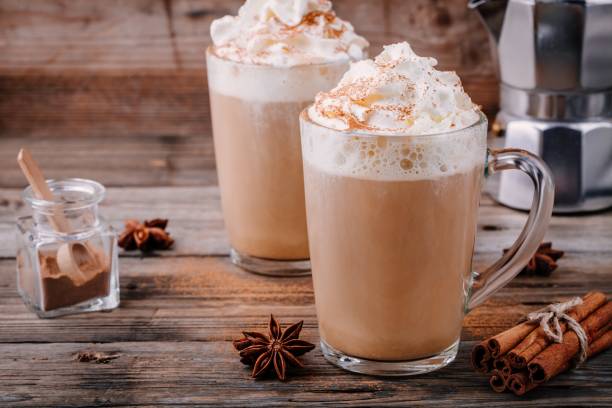 Pumpkin spice latte with whipped cream and cinnamon Pumpkin spice latte with whipped cream and cinnamon in glass on wooden background chai stock pictures, royalty-free photos & images