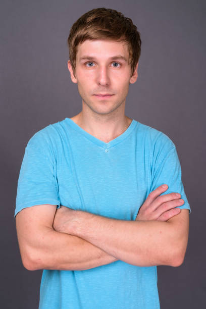 istock Young handsome man wearing blue shirt against gray background 878369392