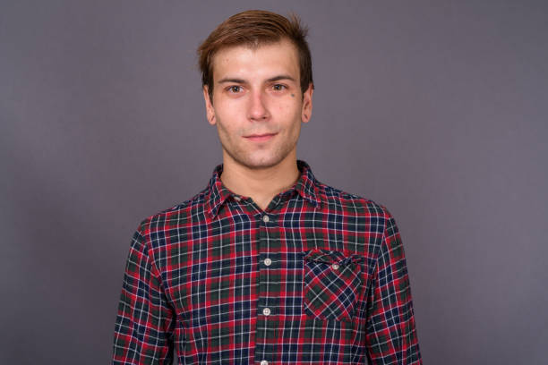 istock Young handsome man wearing checked shirt against gray background 878372060