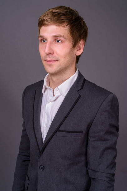 istock Young handsome businessman wearing suit against gray background 878372424