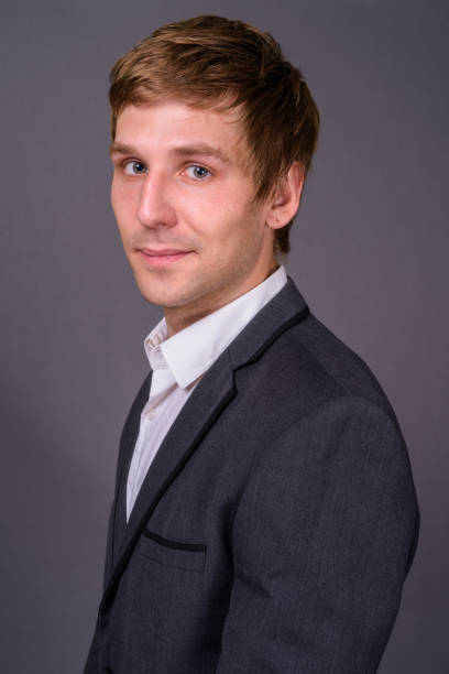 istock Young handsome businessman wearing suit against gray background 878372572