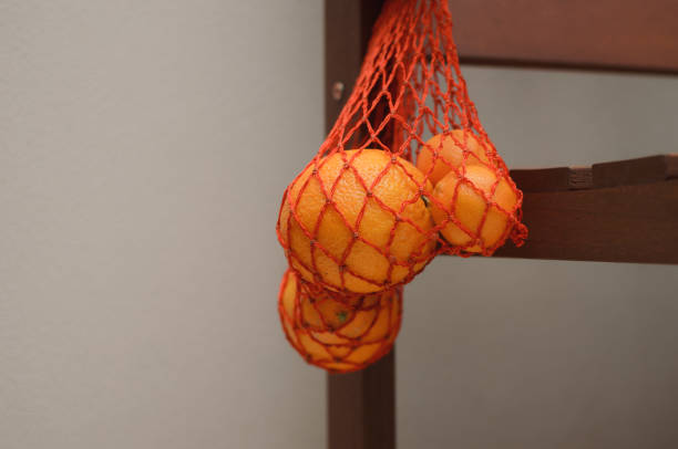 istock Oranges in a string bag on a wooden door 878396068