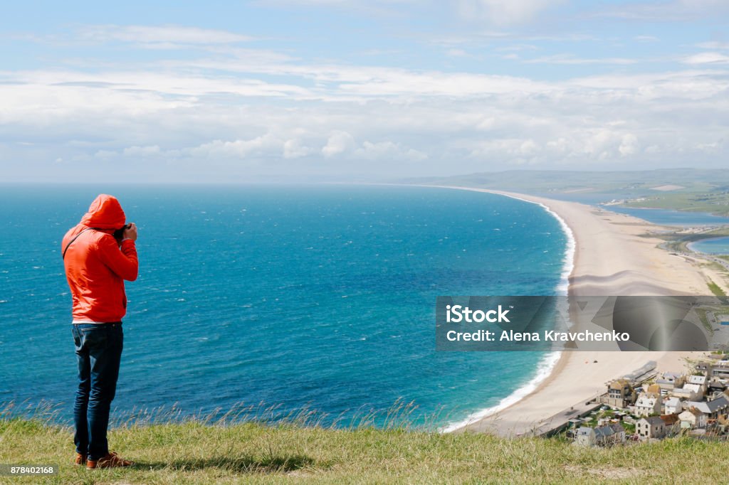 若い男は、イギリスのドーセット州ポートランド島にウェイマスと展望台から海岸線の写真をとります。 - イギリスのロイヤリティフリーストックフォト