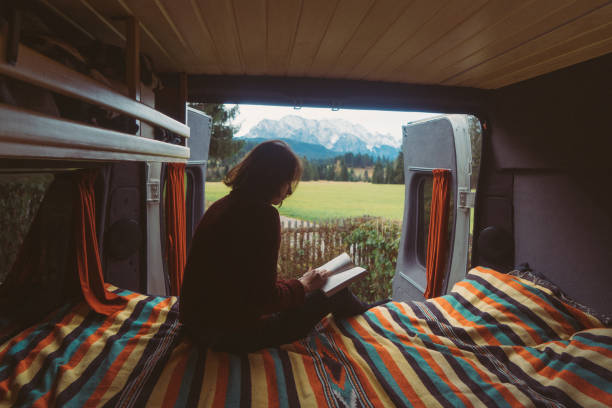 istock Woman reading book  in camper van with view on Alps 878414534