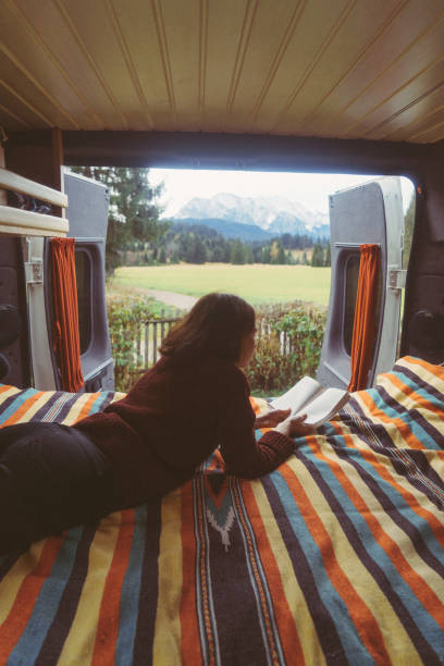 istock Woman reading book  in camper van with view on Alps 878414536