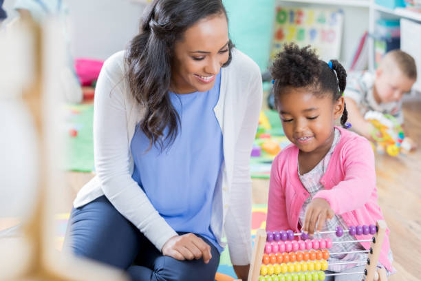 istock Teacher helps preschooler with abacus 878418184