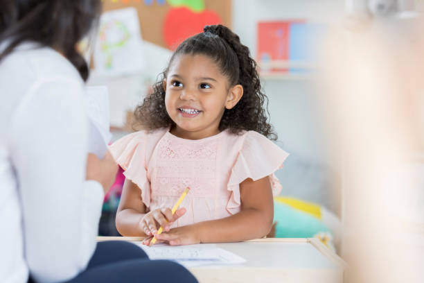 istock Smiling preschooler talks with teacher 878418214