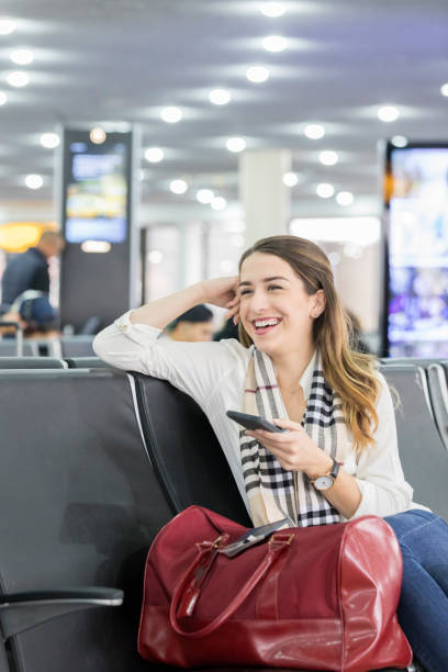 istock Young woman enjoys texting while waiting for international flight 878418628
