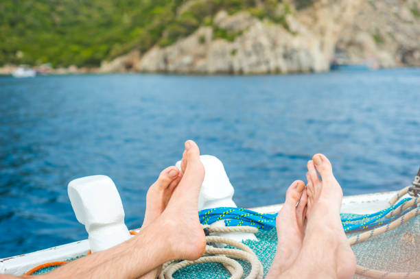 relax durante le vacanze di viaggio in nave da crociera. primo piano di uomini piedi su un balcone con vista sull'oceano sul mare. donna scalzo abbronzarsi rilassandosi presso il centro benessere all'aperto. - balcony human foot men relaxation foto e immagini stock