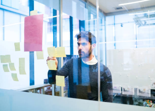 istock Businessman looking at adhesive note on glass 878422426