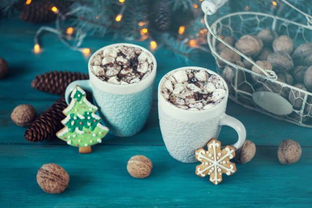 istock Hot chocolate with marshmallows, cinnamon and spices on a blue background with fir and christmas lights 878422564