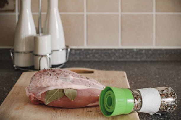 kitchen. on a wooden board a piece of chicken with a laurel leaf, a white set for spices and a mixture of salt and various herbs - poultry shears imagens e fotografias de stock