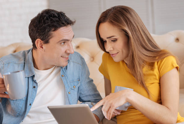 istock Cheerful woman choosing a film on a tablet while sitting and smiling 878426056