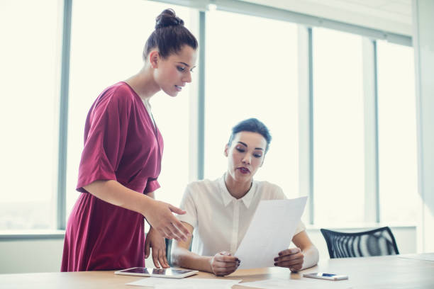 istock Young female business colleagues sharing document 878427102