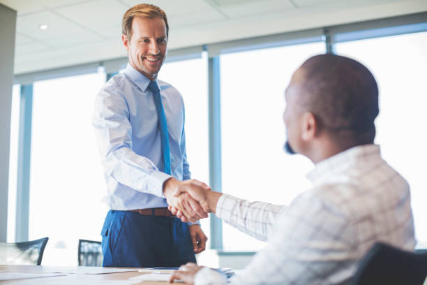 istock Smiling male colleagues shaking hands at office 878433350