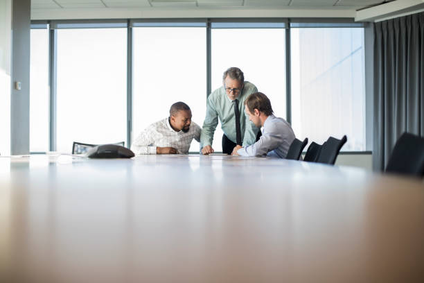 istock Senior businessman sharing tablet with coworkers 878437648