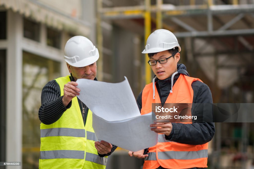 Asiatiques jeunes apprentis au travail sur le chantier de construction avec l’ingénieur principal. À l’extérieur - Photo de Apprenti libre de droits